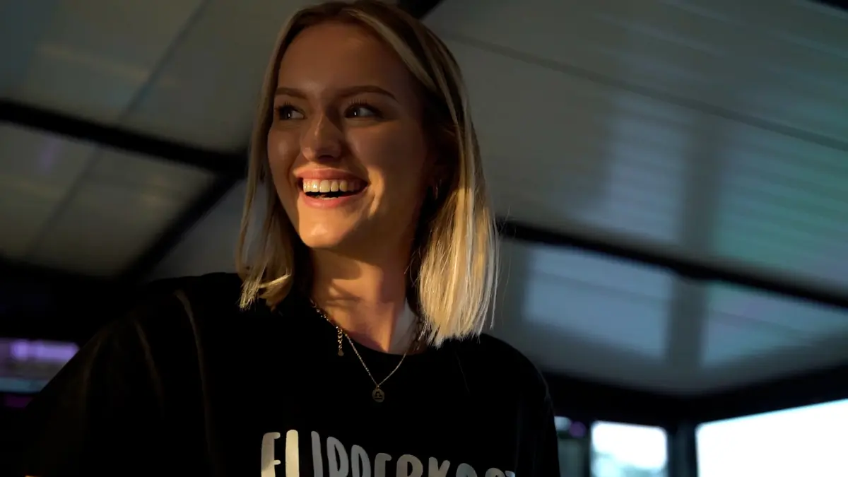 Still uit een bedrijfsfilm: een lachende medewerker in warm licht